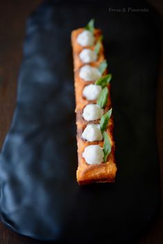 a black plate topped with food and garnish on top of a wooden table