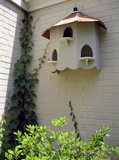 a white bird house hanging from the side of a building