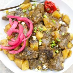 a white plate topped with meat and veggies next to a knife and fork