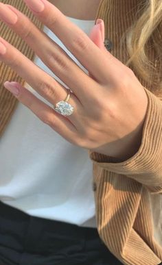 a woman's hand with a diamond ring on her left hand and a brown cardigan sweater