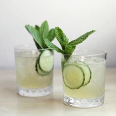 three shot glasses filled with limeade and rosemary garnish on a piece of wood