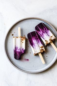 three popsicles with purple and white toppings on a plate