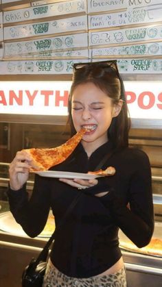 a young woman eating a slice of pizza