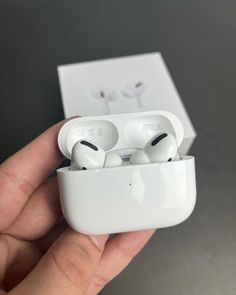 a person holding an apple airpods in their left hand, with the box open