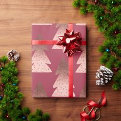 a present wrapped in green paper with red ribbon and bows on it next to christmas decorations