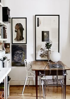 a dining room table with chairs and pictures on the wall