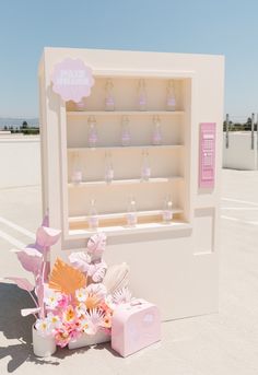 a pink and white display case with flowers in it