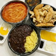 four different types of food are in bowls on the table, including noodles and sauces