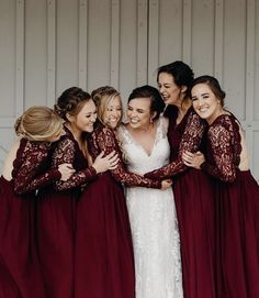 a group of women standing next to each other wearing long sleeves and maroon gowns