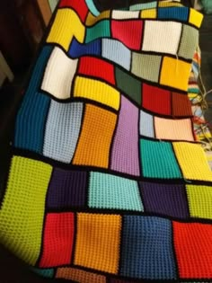 a multicolored crocheted blanket sitting on top of a table