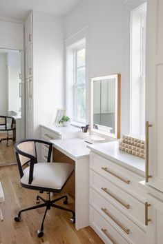 a white desk with a chair in front of it and a mirror on the wall