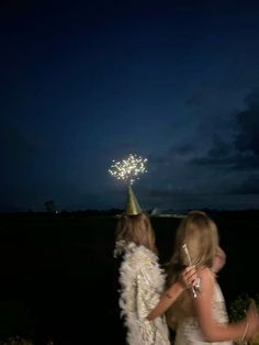 two girls in white dresses are looking at fireworks