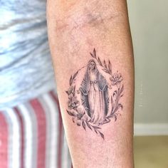 a woman's arm with a tattoo on it that has a virgin mary in the center