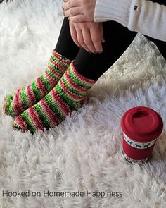 a woman sitting on top of a white rug next to a coffee cup and socks