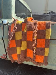 an orange and brown blanket sitting on the back of a truck