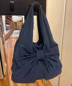 a blue purse with a large bow hanging from it's front end on a hook