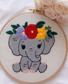 an elephant with flowers in it's head sitting on a bed next to roses