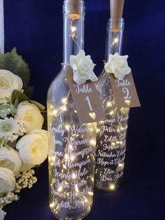 two wine bottles decorated with lights and flowers