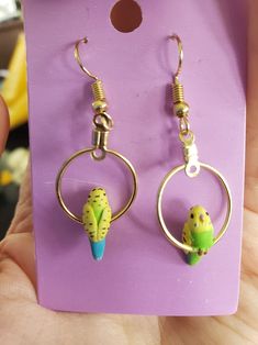 a pair of earrings with cactus charms hanging from it's earwires in front of a purple background