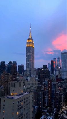 the empire building is lit up at night in new york city, ny on an overcast day