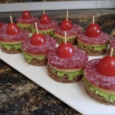 small appetizers are arranged on a white plate with toothpicks in them