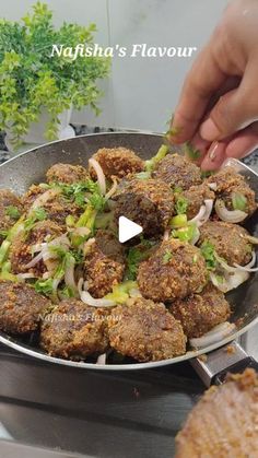 someone is cooking food in a pan with onions and meatballs on the stove top