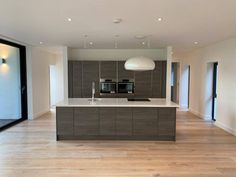 an empty kitchen with wooden floors and white walls, along with glass doors leading to the outside