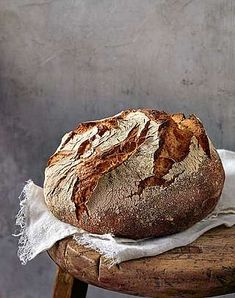 a loaf of bread sitting on top of a wooden stool next to a white cloth