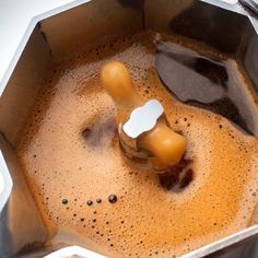 a metal pan filled with liquid and an object in the bottom right hand corner that appears to be melting