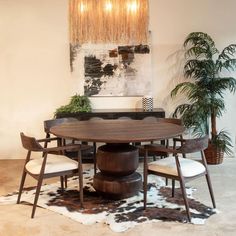 a dining room table with four chairs and a cow hide rug on the floor in front of it