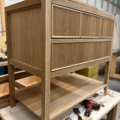 a wooden dresser with drawers on it in a room filled with woodworking tools and other items