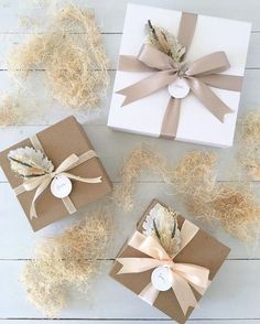 three gift boxes wrapped in brown and white paper with feathers on them, sitting next to each other