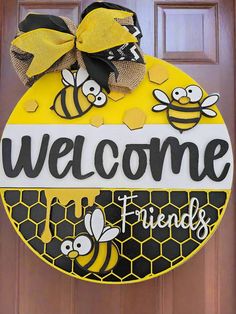 a yellow and black welcome sign hanging on the front door to a house with bees painted on it