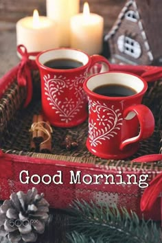 two cups of coffee sitting on top of a tray next to some flowers and candles