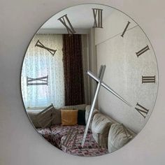 a large round mirror with roman numerals on the face and behind it is a couch