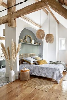 a bedroom with wood floors, white walls and wooden beams on the ceiling is decorated in natural materials