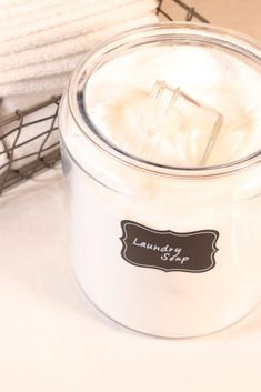 a white candle sitting on top of a table next to a basket and towel dispenser