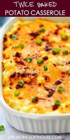 a casserole in a white dish topped with cheese and green onions, on a table