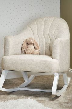 a white rocking chair with a stuffed animal on it's back in a room