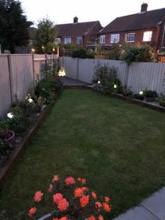 the backyard is lit up with some lights and flowers in blooming pots on the lawn