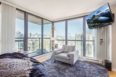 a living room with large windows and a tv mounted to the side of it's wall