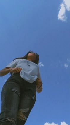 a woman is flying a kite in the sky with her eyes closed and one hand on her hip