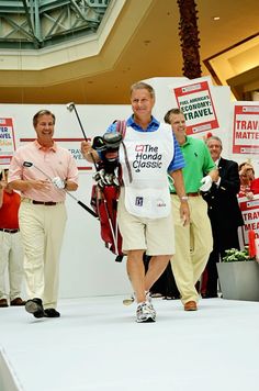 the man is walking down the runway with his golf club