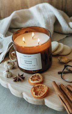 an orange slice sits next to a candle and some cinnamons on a wooden tray