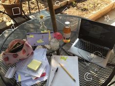 a laptop computer sitting on top of a glass table covered in papers and other items