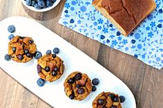 some blueberries and cookies are on a white plate next to a bowl of fruit