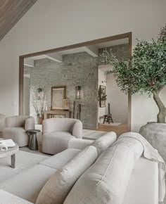 a living room filled with white furniture and a tree in the middle of the room