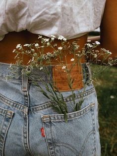 a woman with her back to the camera holding flowers in her pocket