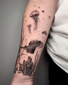 a woman's arm with an octopus and jellyfish tattoo on it, along with other sea creatures