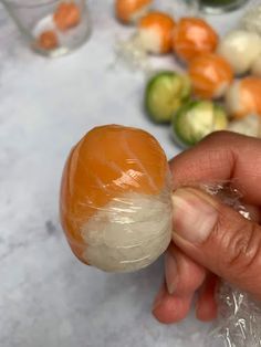 someone holding an egg in their hand with other vegetables around it on the table behind them